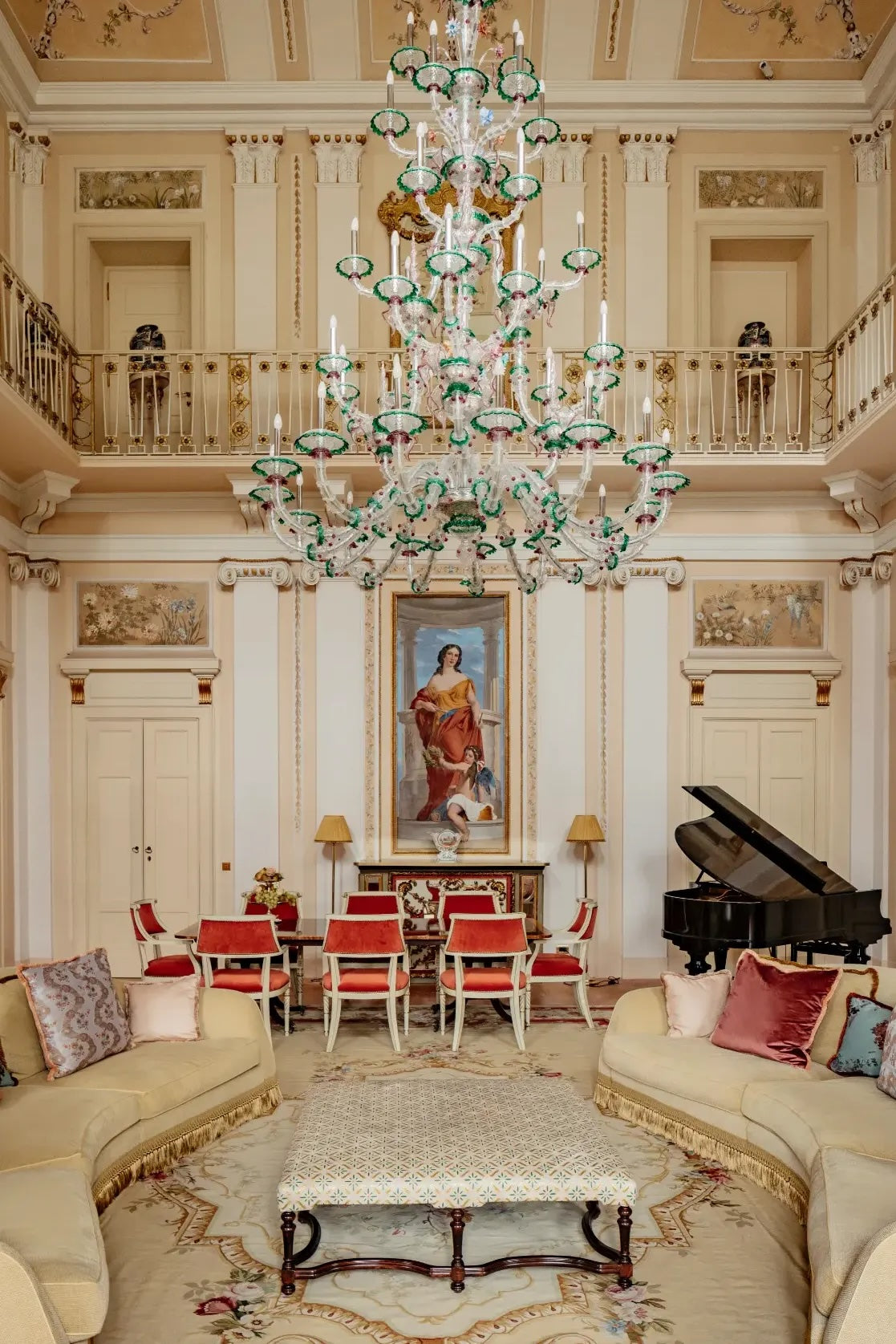 lounge with a piano and red chairs and grand chandelier