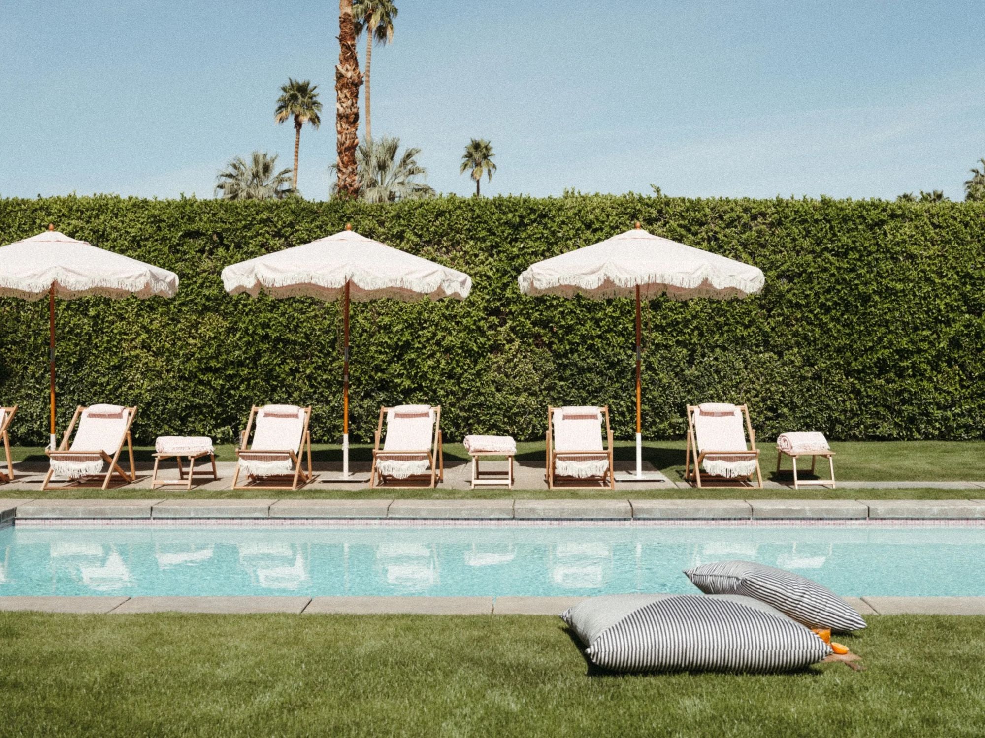 Lauren's Pink Stripe Market Umbrellas and Sling Chairs by a poolside