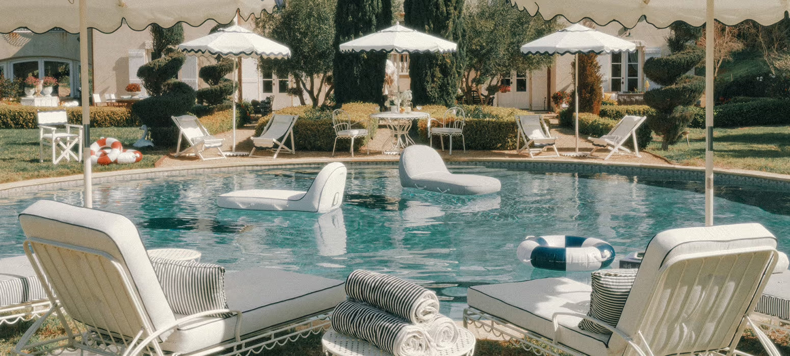 Pool scene with whote sun loungers, towels and umbrellas