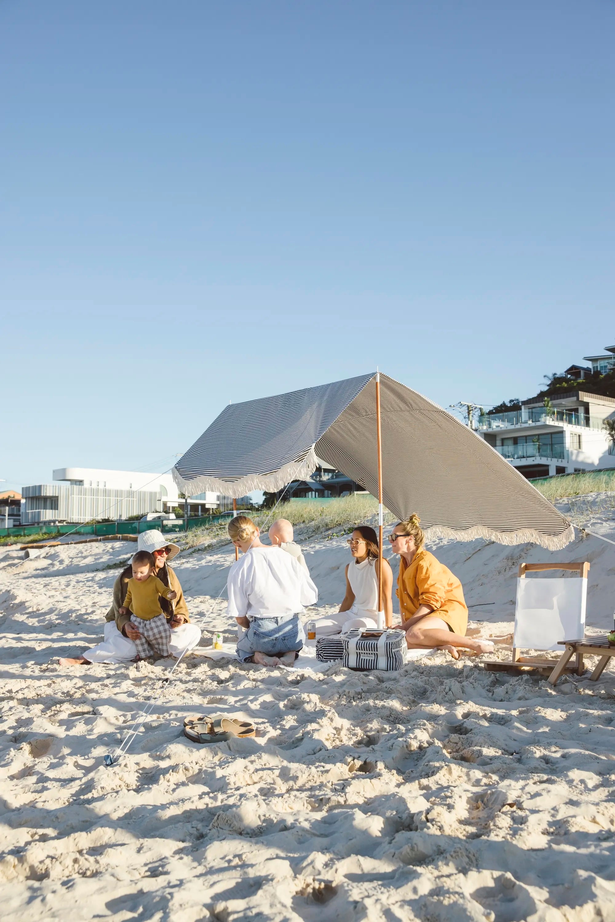 Family under a navy striped beach tent