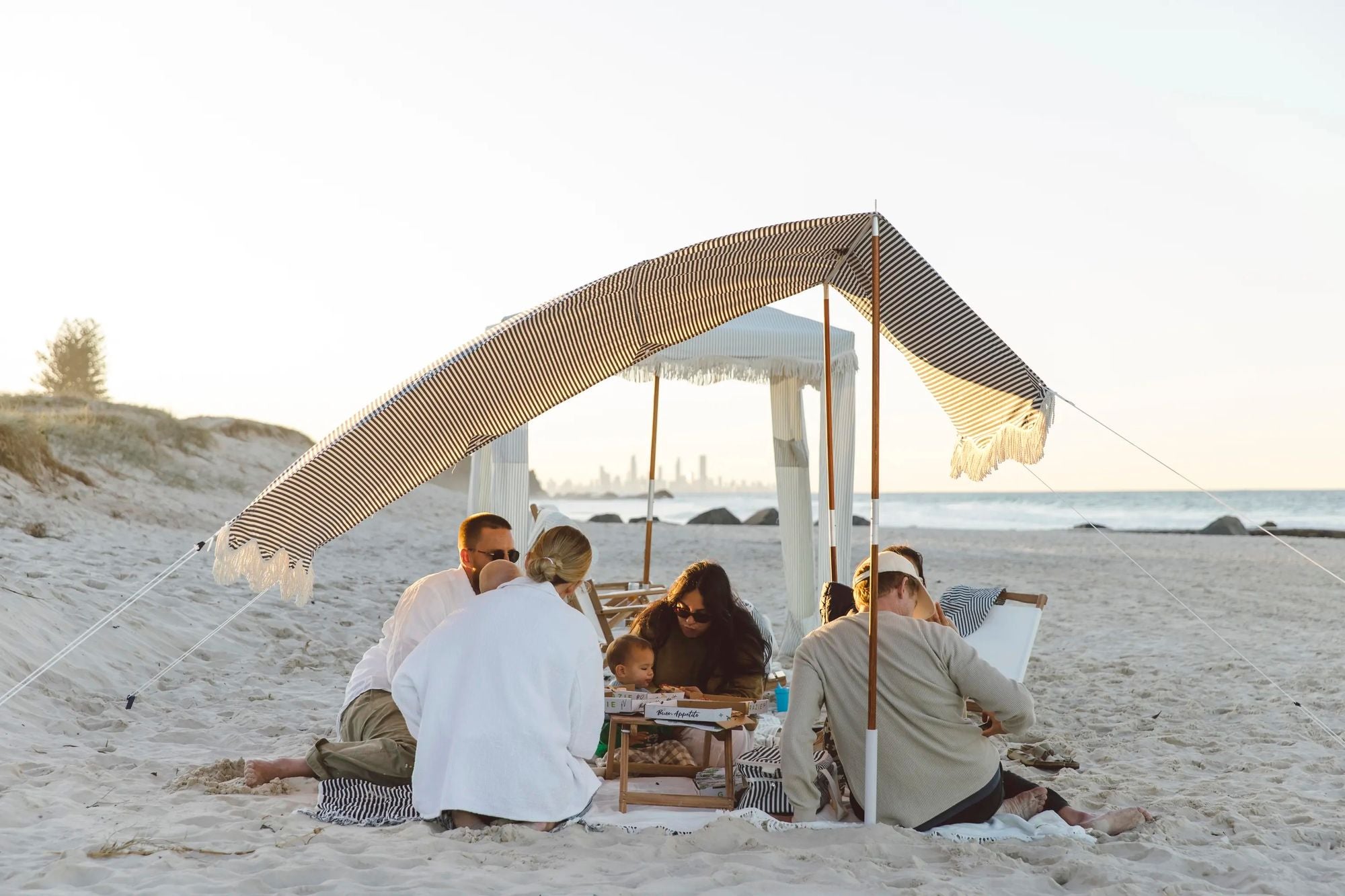 Family beach time under a beach tent at sunset