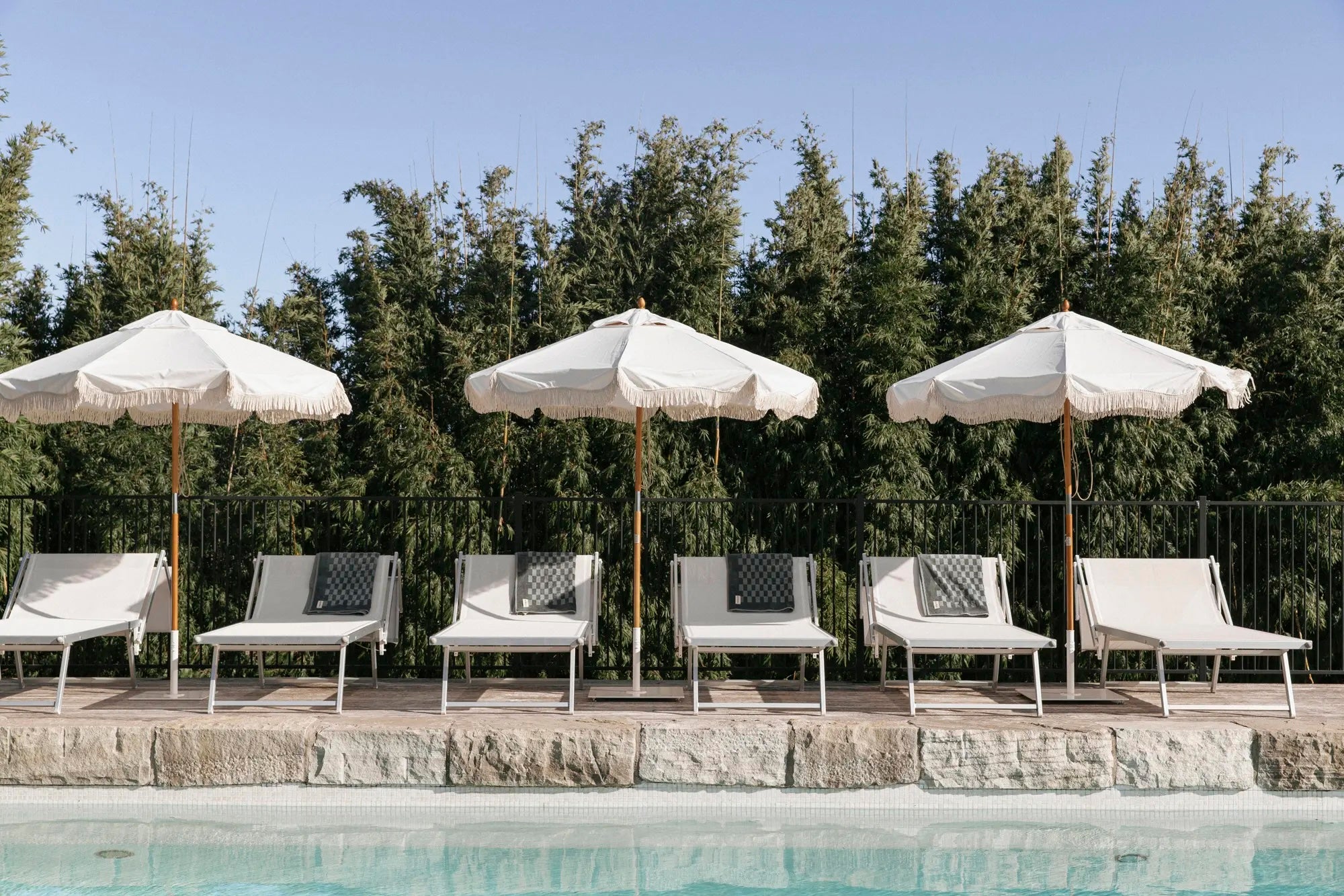 White market umbrellas by a pool with sun lounger chairs