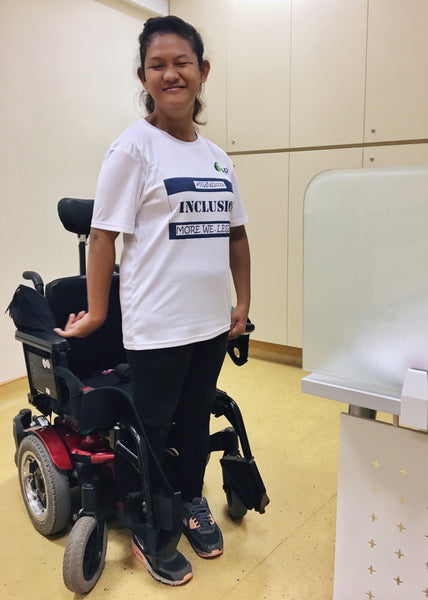 Syafiqah standing by her wheelchair in sporty attire