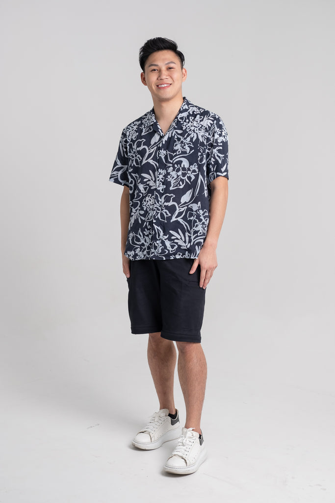 Gavin, a young Chinese man, wearing the Tropical Short Sleeve Shirt in Navy and Convertible Cargo Pants in Black. The Cargo Pants has been transformed into a pair of shorts.