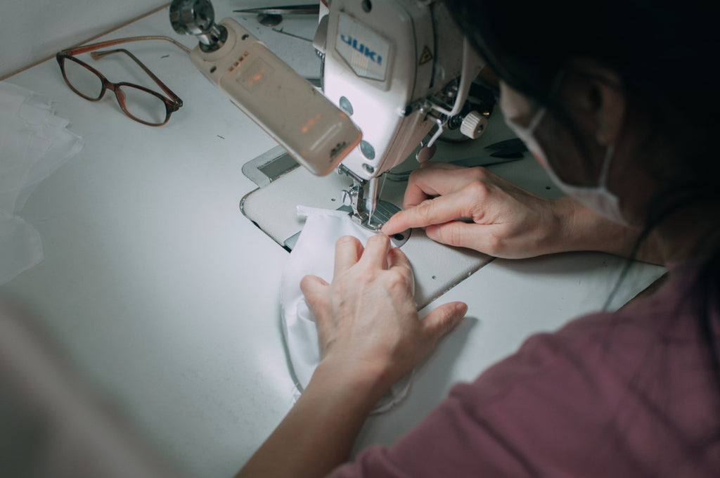 Close up of seamstress working on a face mask with a sewing machine.