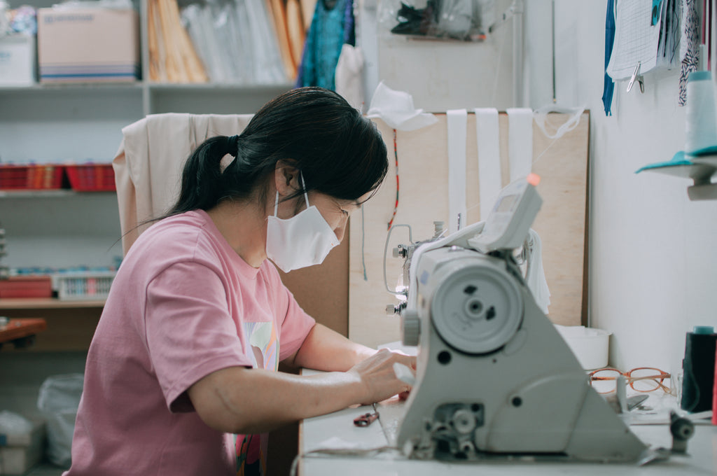 Middle-aged female employee in a pink shirt, working with a sewing machine
