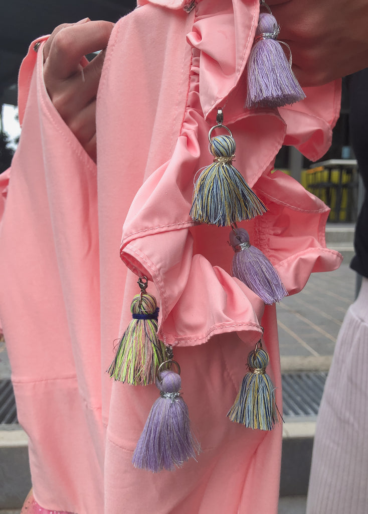 Colourful tassles with mini hooks dangles from the sleeves of the dress around the shoulder.