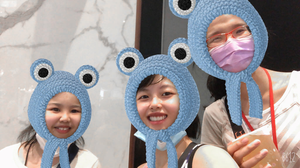 Elisa and two female craftsmen having fun with a blue frog AI filter on their heads.