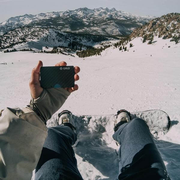 Male holding Carbon fiber wallet snowboarding in California 