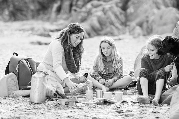 Woman sitting on the beach with two girls having a picnic