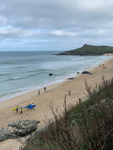 Porthmeor Beach with surfers walking across it