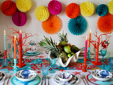 Bright and vibrant tablescape with pompoms and coral candleholders in reds and blues