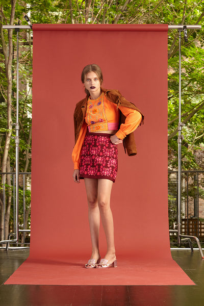 Cynthia Rowley Resort 2017 look 9 featuring a bright orange long sleeve shirt and a red printed mini skirt