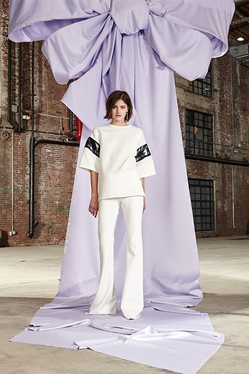 Cynthia Rowley Fall 2017 Look 5 featuring an oversize jersey t-shirt with purple and black sequin stripes on sleeves and white jersey flare pants