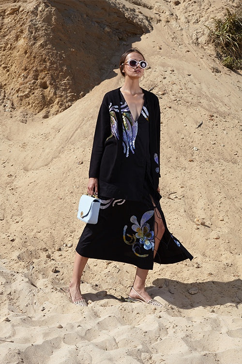 Cynthia Rowley Spring 2016 look 2 featuring a black polished cotton v-neck midi dress with side slit and sequin embellishments and black cardigan with sequin embellishments