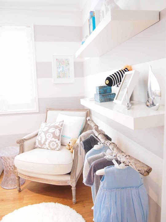 Striped and Serene Nursery White and beige striped childs bedroom with wooden branch clothes rail and white shelves