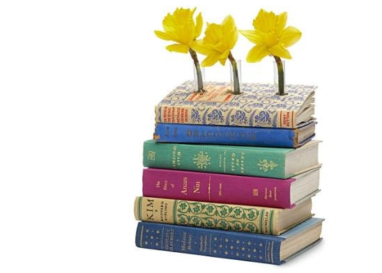 A pile of books with flowers growing through them