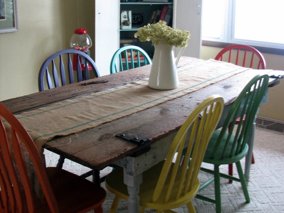 Colourful recycled chairs around a wooden table