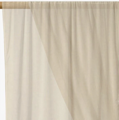 Cream coloured voile fabric hanging from a curtain pole.