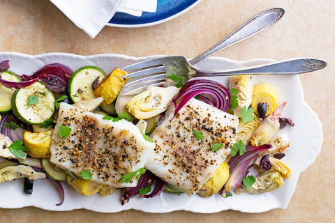 Baked cod with olives, artichoke hearts, zucchini, squash, and red onions.