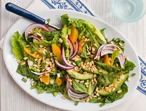 Salad with oranges, pine nuts, avocado, and onions.