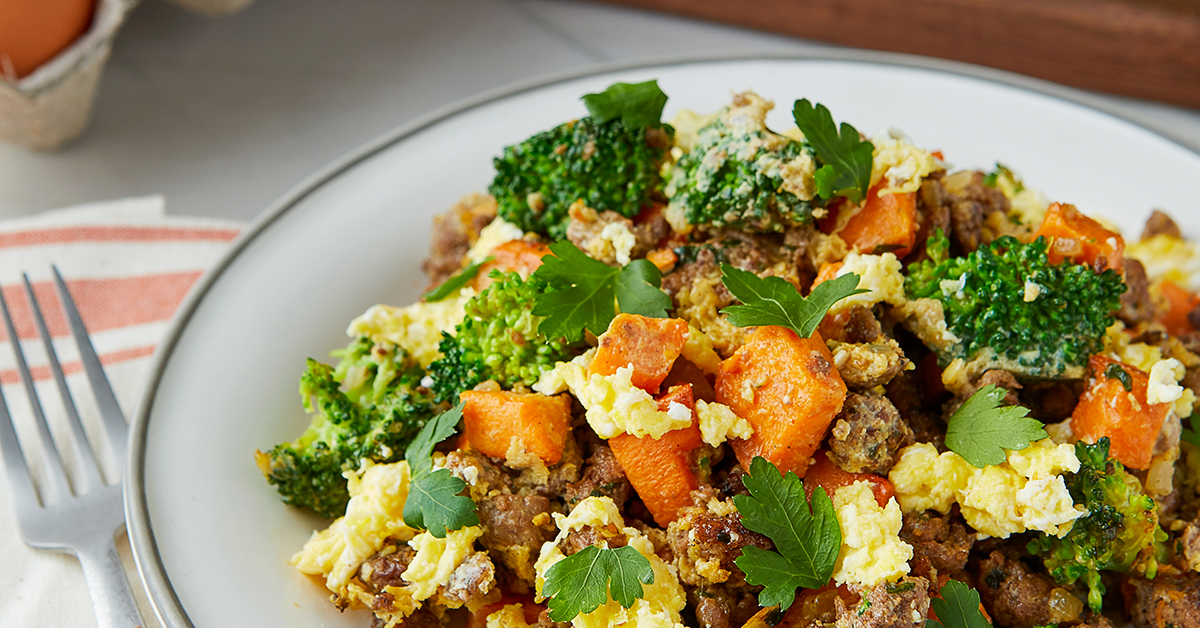 Close up of spiced lamb scramble with sweet potatoes, eggs, broccoli, and parsley.