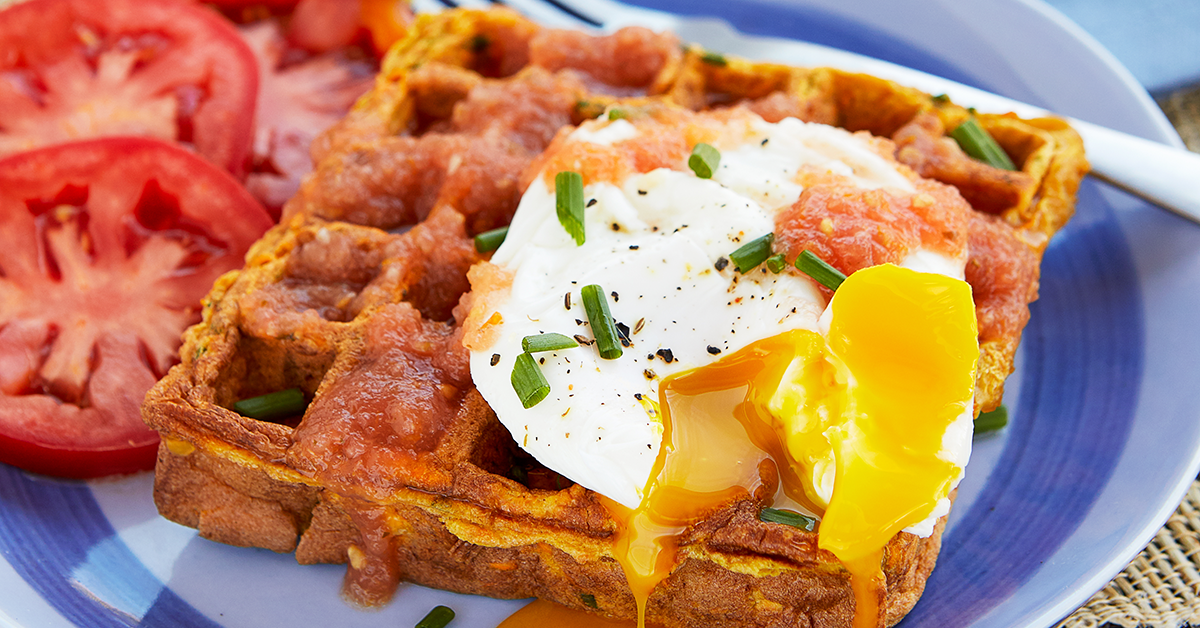 Close up of waffle made with sweet potatoes with a poached egg on top.