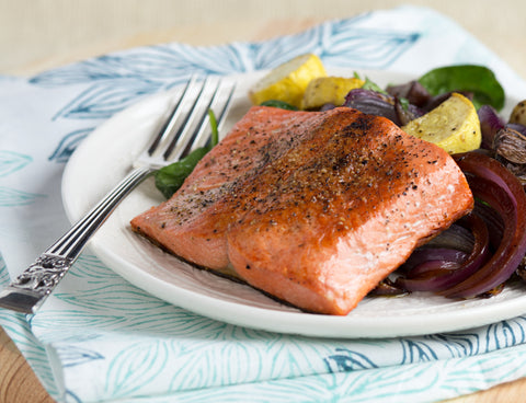 Close up of salmon on a plate with mixed vegetables.