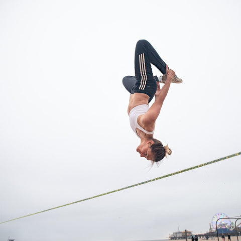 Olga Henry slacklining, in the air, upside down. 