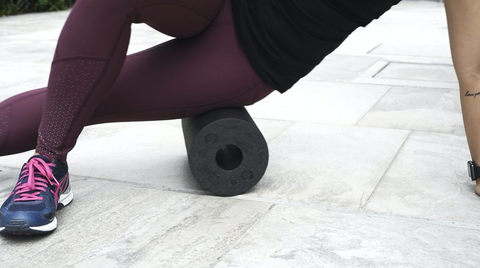 Woman using the BLACKROLL Standard Foam Roller in black to foam roll thighs