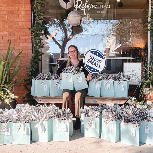 Woman with gift bags and "Shop Small" sign
