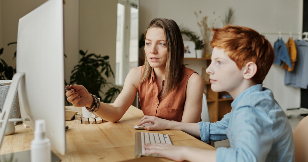 Woman teaching boy with a computer