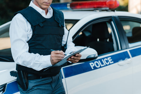 Policeman wearing a bulletproof vest in front of a police car