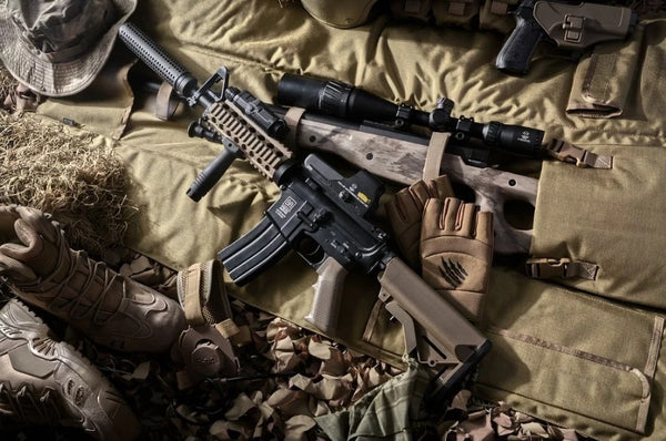 Rifle gun, tactical gloves, military boots, and other military equipment laid out on the floor