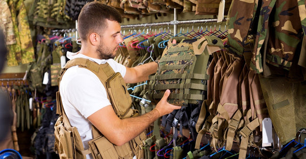 Man inspecting a multicam plate carrier in a body armor shop