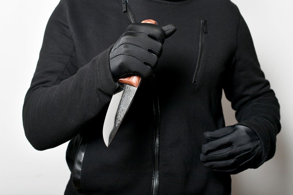 image of a man in dark clothing  holding a knife
