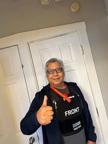 A man wearing a bulletproof vest and giving a thumbs-up