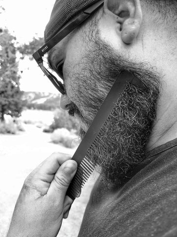 A man combing his beard with a Steeltooth dresser comb.