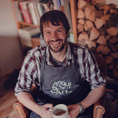 Angus Grant smiling with a cup of tea. 