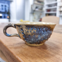 Handmade clay cup sitting on a shelf