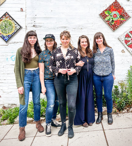 Image of band members of Della Mae, from left to right: Maddie Witler (mandolin), Kimber Ludiker (fiddle and vocals), Celia Woodsmith (guitar and vocals), Vickie Vaughn (bass and vocals), and Avril Smith (guitar). 