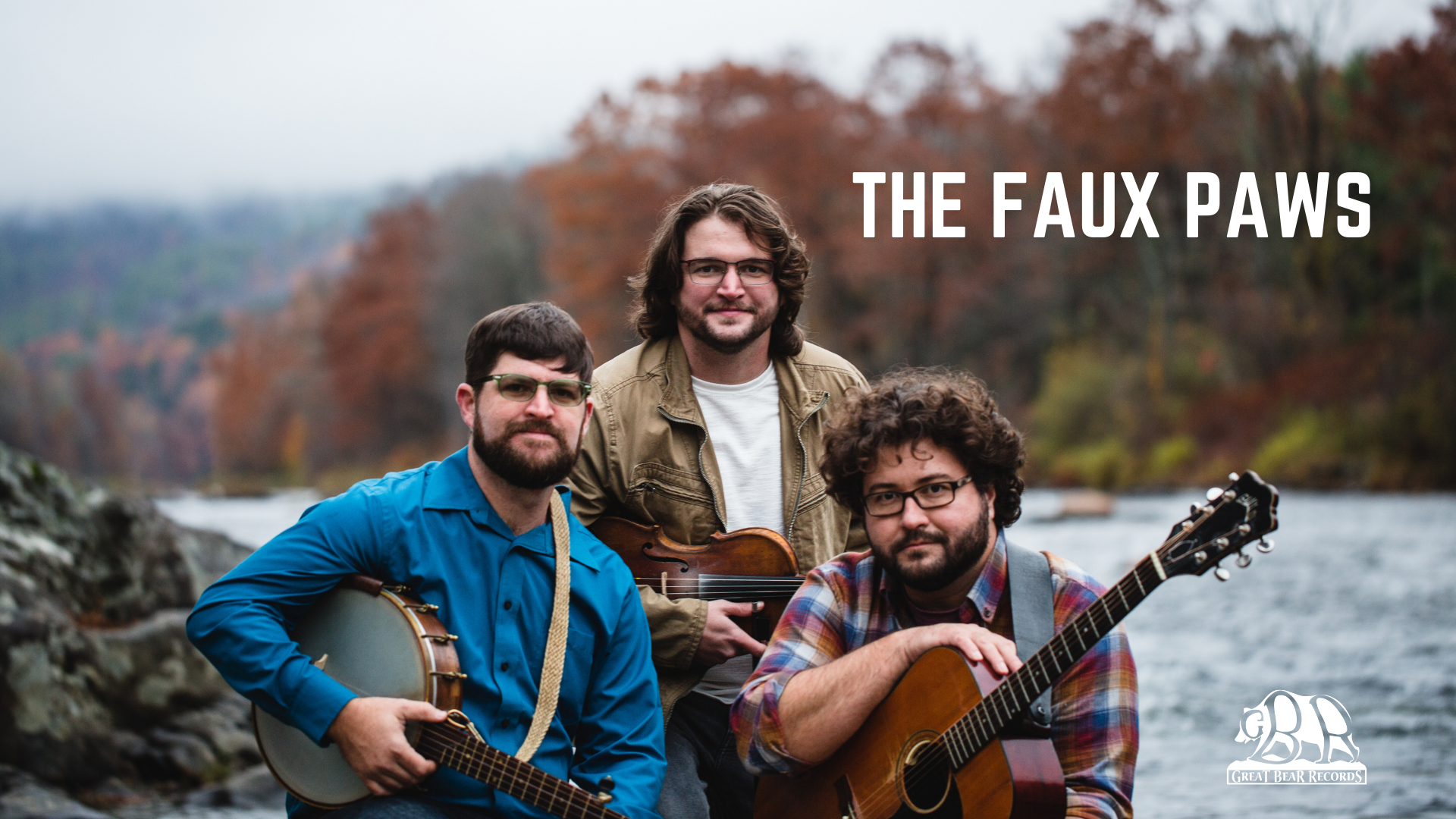 Promo image of the band The Faux Paws, holding their instruments and standing by a river with trees in the background.