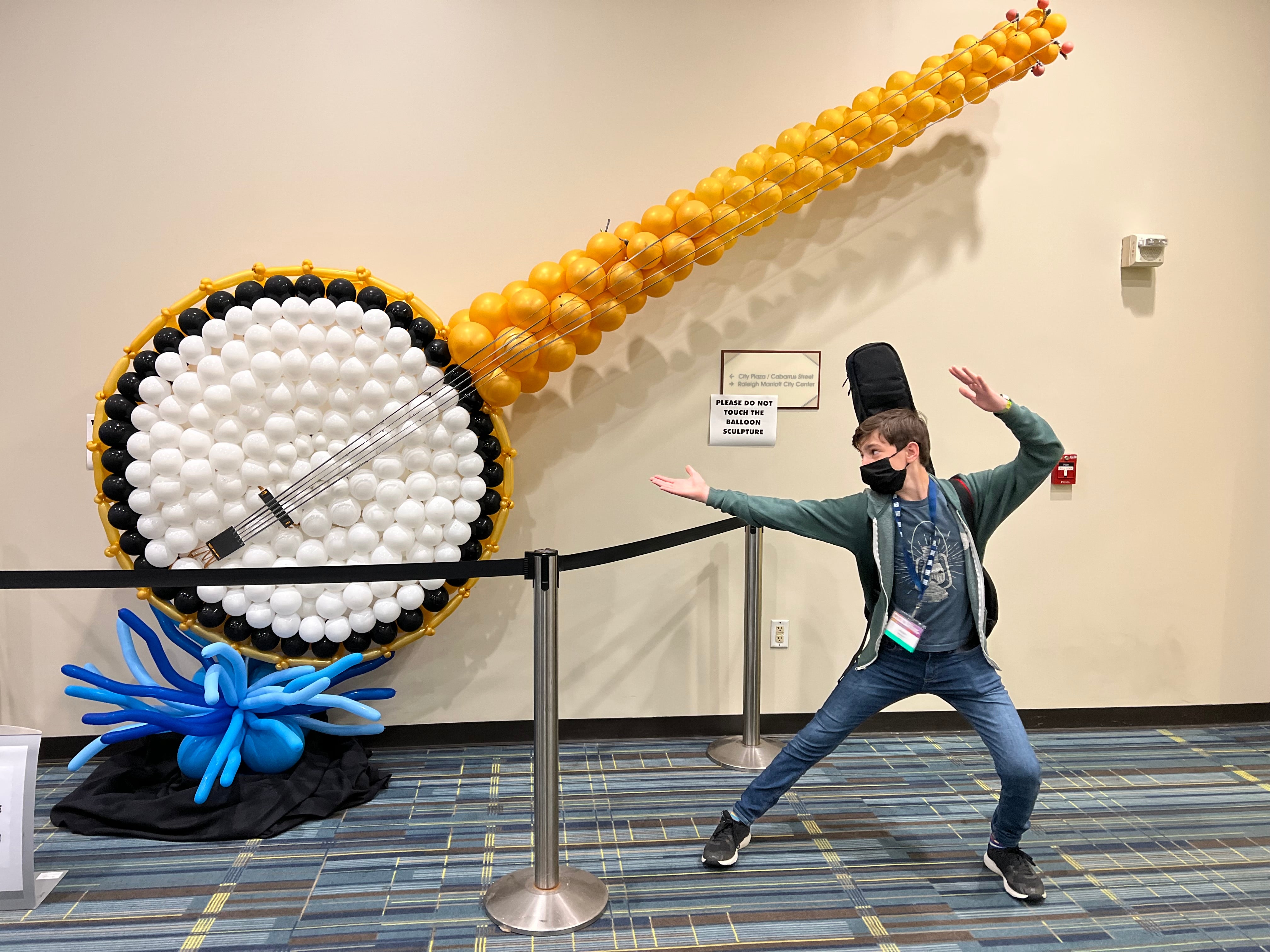 Image of the author, 14-year-old Nikolai Margulis, posing in front of the IBMA World of Bluegrass banjo balloon art display.