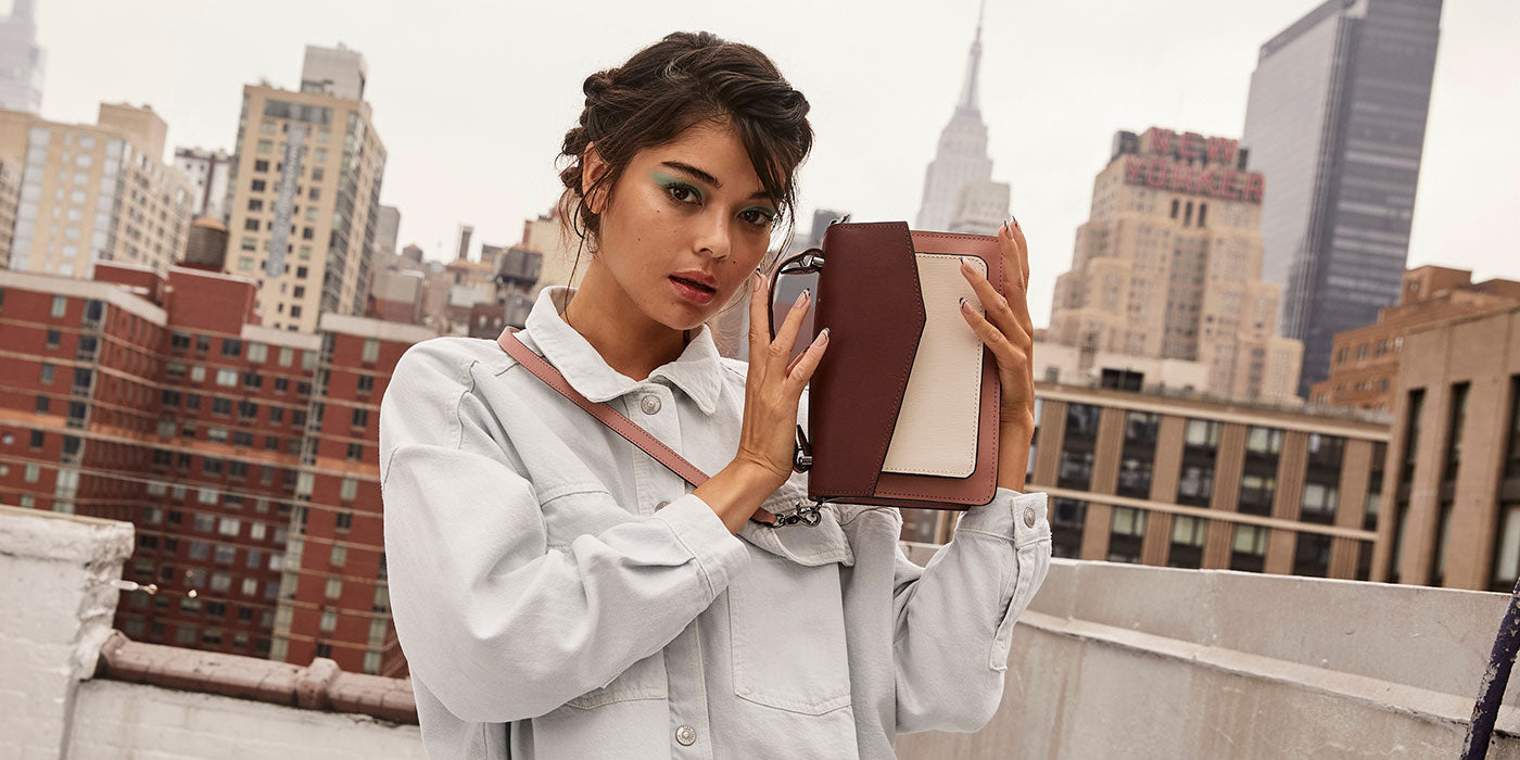 Model holding Cobble Hill crossbody in wine red and rose pink color