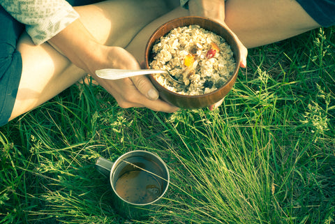 A person eats oatmeal with dried fruit and a cup of tea for their breakfast.