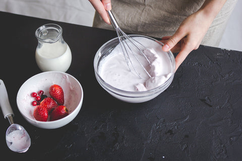 A person mixed their homemade ice cream in a bowl with toppings nearby.