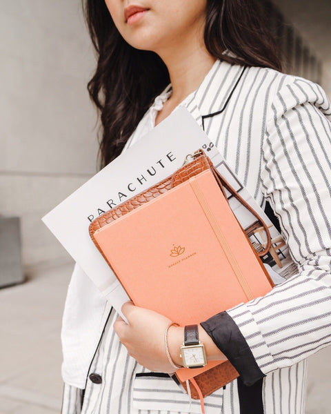 Woman in striped blazer holding a pink Ponderlily Weekly Planner