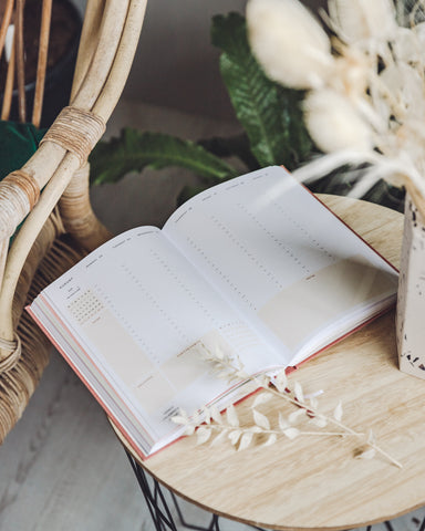 Ponderlily Planner open at the weekly view page, on natural wood with dried foliage