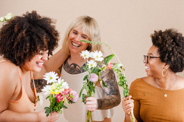 Three models laughing while holding flowers