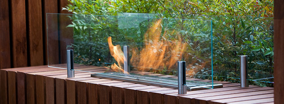 Wood looking firepit with custom bioethanol burner with tall glass wind guards blocking the flame